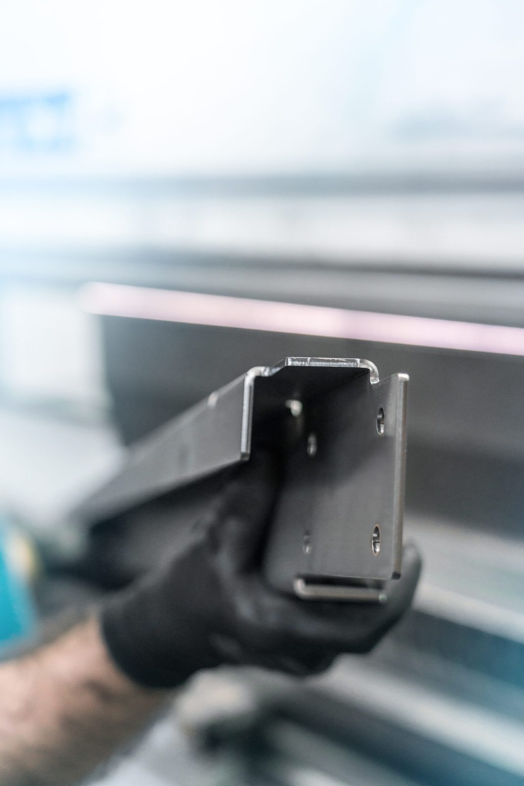Bent U-profile sheet metal part in a gloved hand