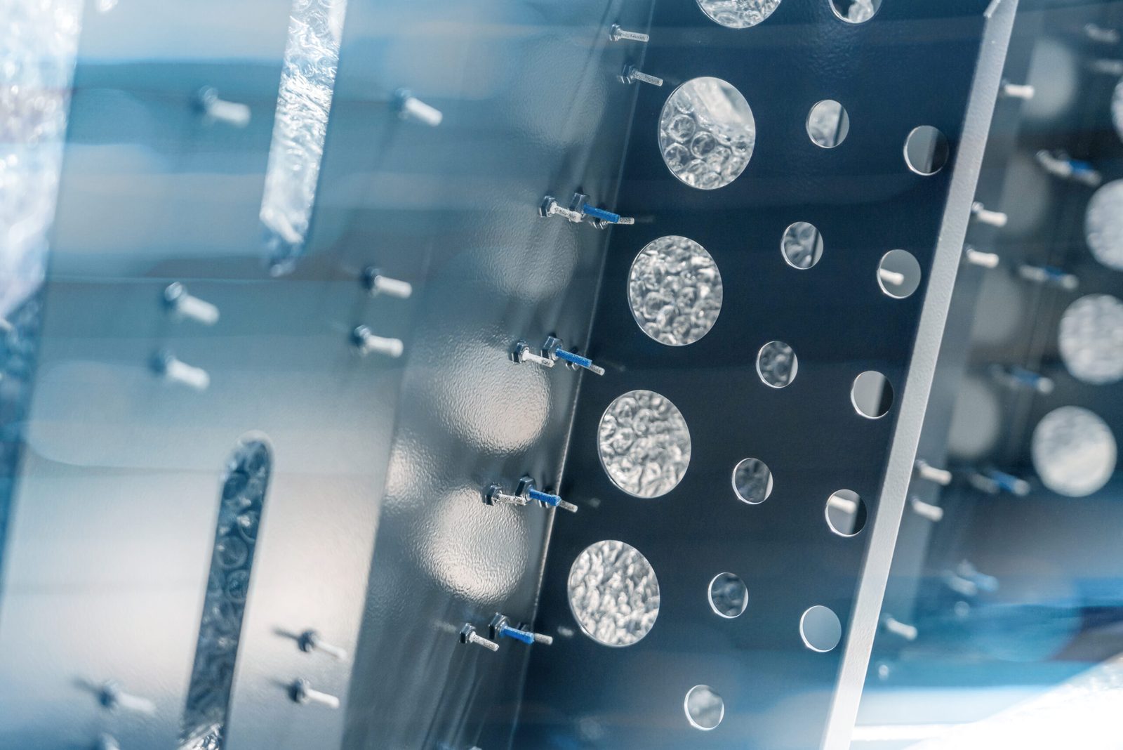 Sheet metal part with welded studs and punched holes, partly covered with protective film