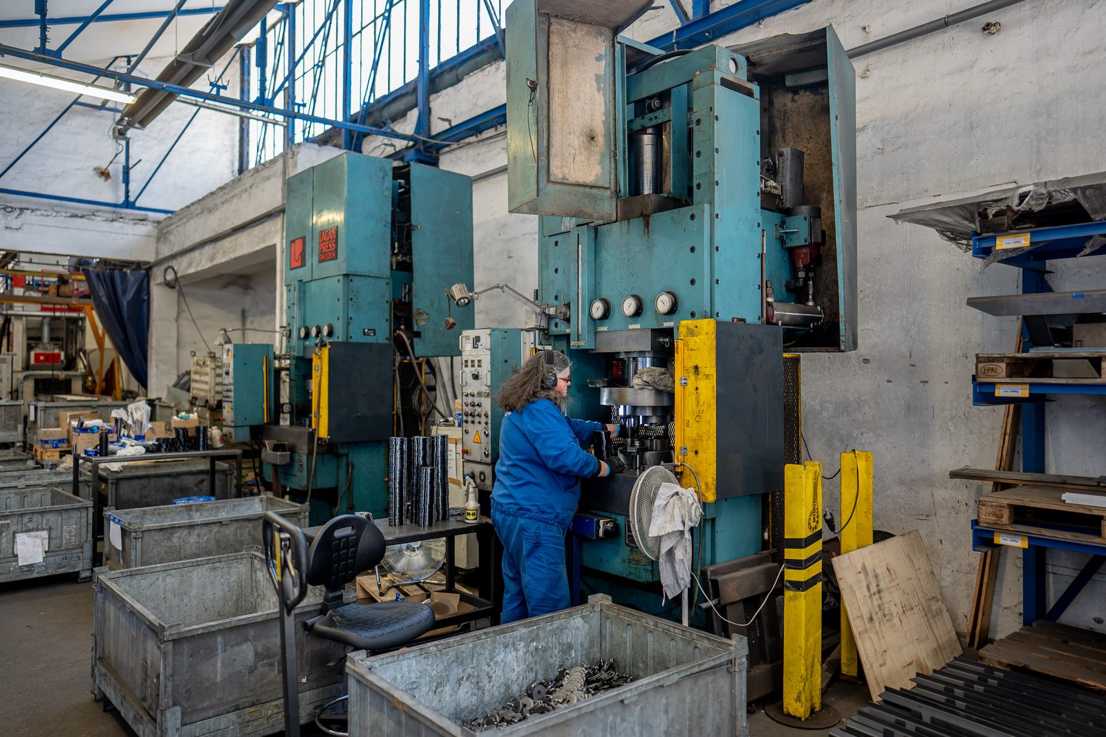 Bedienerin an einer Hydraulikpresse mit Teilekisten